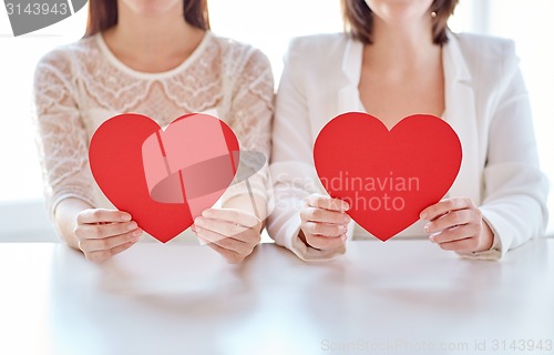 Image of close up of happy lesbian couple with red hearts
