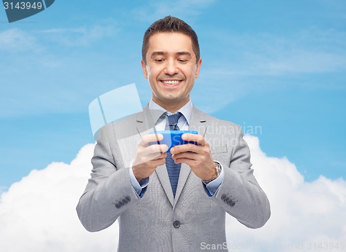 Image of happy businessman texting on smartphone