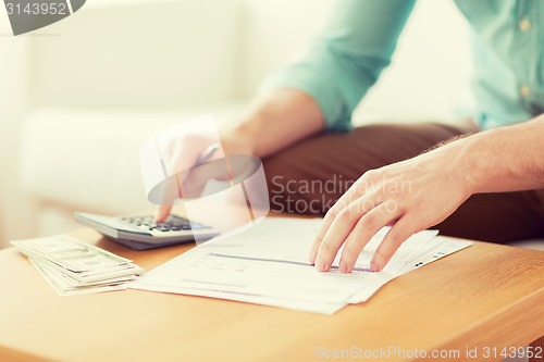 Image of close up of man counting money and making notes