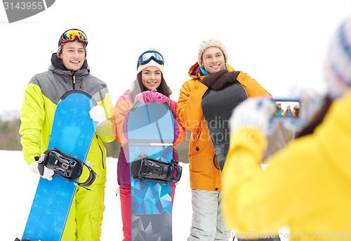 Image of happy friends with snowboards and smartphone