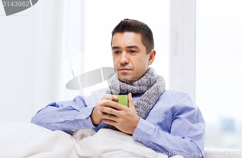 Image of ill man with flu drinking hot tea from cup at home