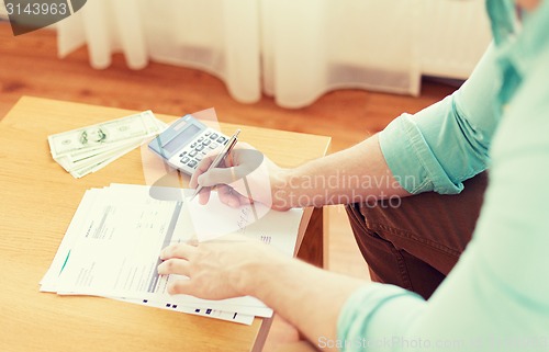 Image of close up of man counting money and making notes