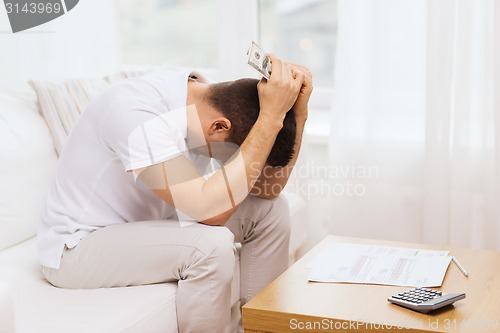 Image of man with money and calculator at home