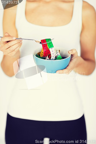 Image of woman hands holding bowl with measuring tape