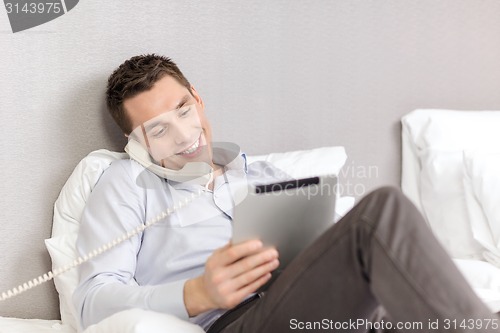 Image of businessman with tablet pc and phone in hotel room