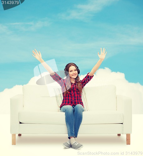 Image of teenage girl sitting on sofa with headphones