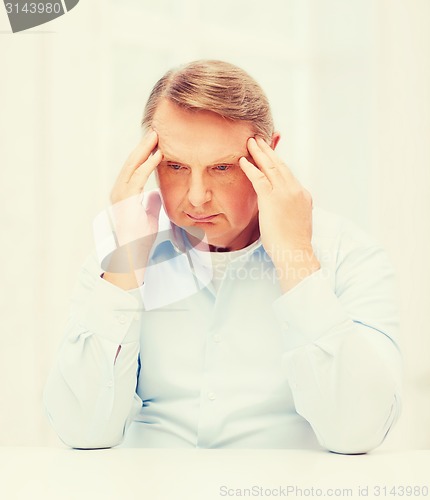 Image of stressed old man holding head at home