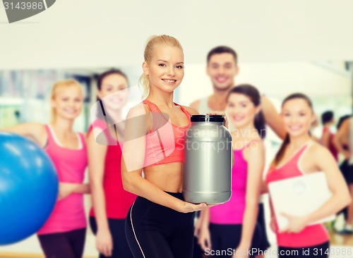 Image of smiling sporty woman with jar of protein