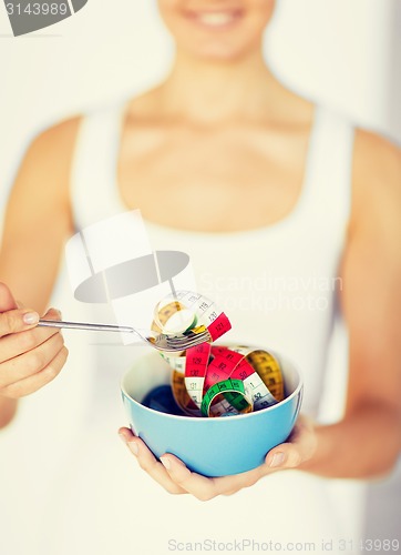 Image of woman hands holding bowl with measuring tape