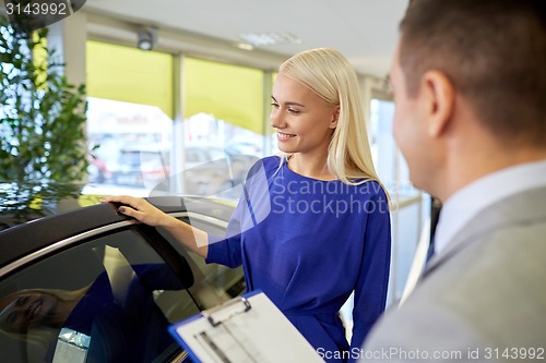 Image of happy woman with car dealer in auto show or salon