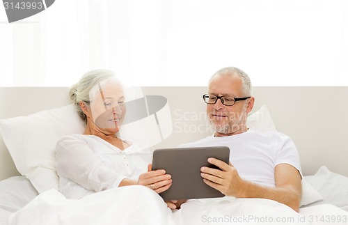 Image of happy senior couple with tablet pc at home