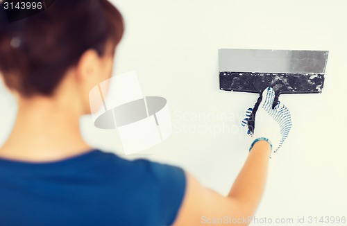 Image of woman plastering the wall with trowel