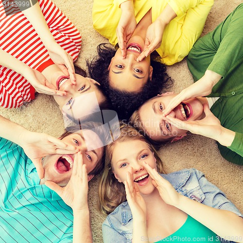 Image of smiling people lying down on floor and screaming