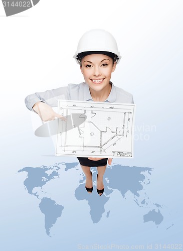 Image of businesswoman in helmet showing with blueprint