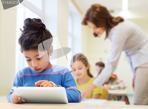 Image of little school girl with tablet pc over classroom