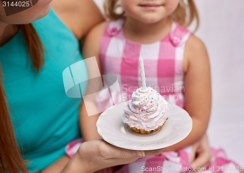 Image of happy mother and little girl holding cupcake