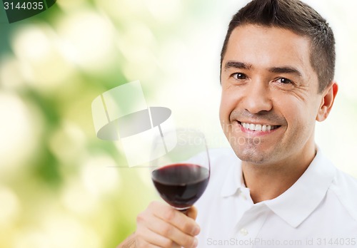 Image of happy man drinking red wine from glass