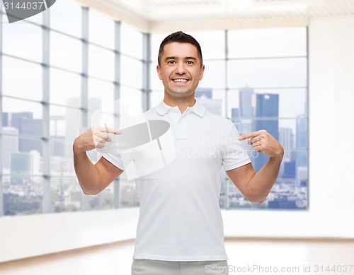 Image of smiling man in t-shirt pointing fingers on himself