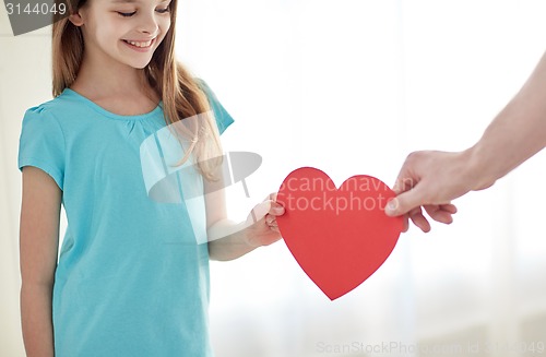 Image of close up of girl and male hand holding red heart