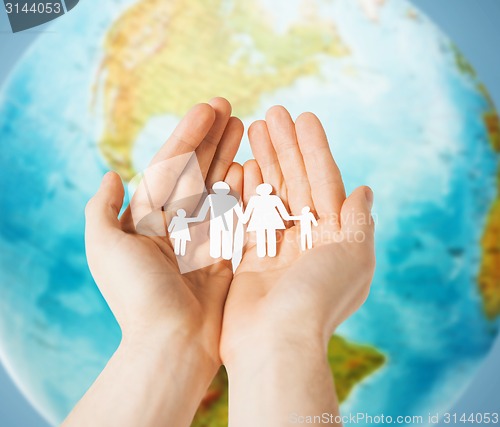 Image of human hands holding paper family over earth globe