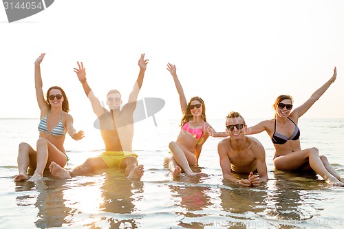 Image of smiling friends in sunglasses on summer beach