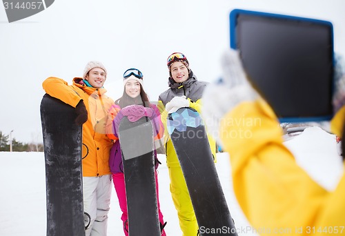 Image of happy friends with snowboards and tablet pc