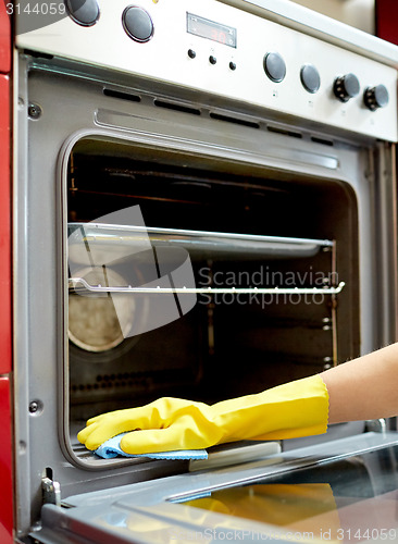 Image of close up of woman cleaning oven at home kitchen