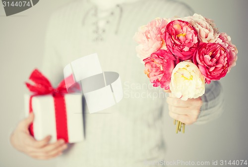 Image of man holding bouquet of flowers and gift box