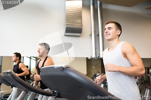 Image of smiling men exercising on treadmill in gym