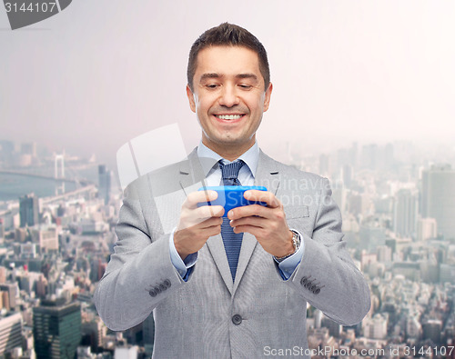 Image of happy businessman texting on smartphone