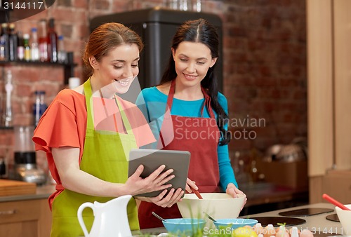 Image of happy women with tablet pc cooking in kitchen