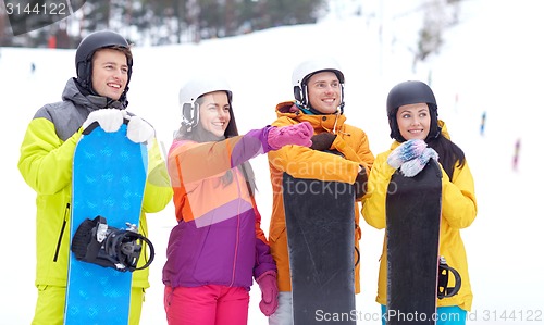 Image of happy friends in helmets with snowboards