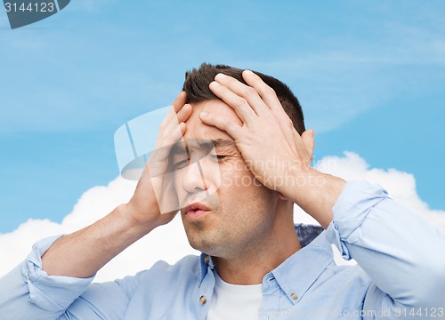 Image of unhappy man with closed eyes touching his forehead