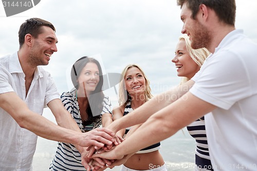 Image of smiling friends putting hands on top of each other