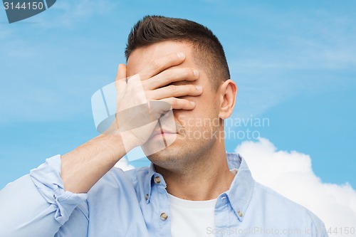 Image of unhappy man covering his eyes by hand