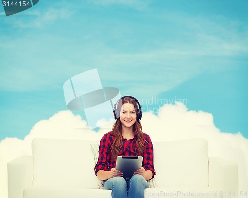 Image of girl sitting on sofa with headphones and tablet pc