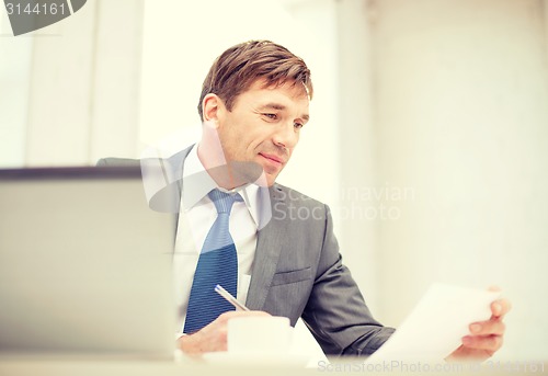 Image of businessman with laptop computer and documents