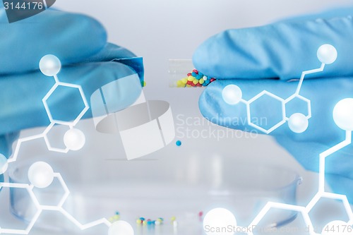 Image of close up of scientist hands holding pill in lab