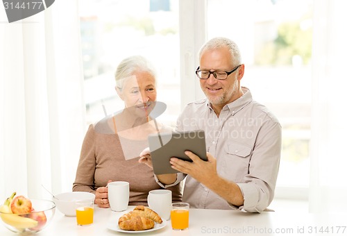 Image of happy senior couple with tablet pc at home