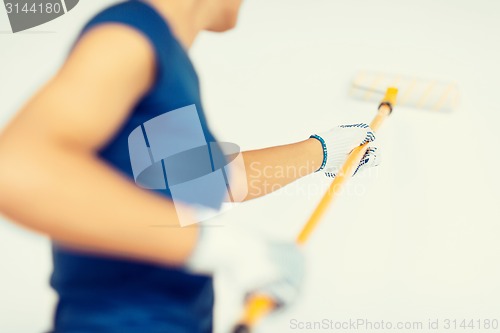 Image of woman with roller and paint colouring the wall