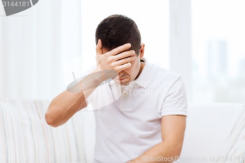 Image of unhappy man suffering from head ache at home