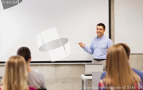 Image of group of students and smiling teacher in classroom