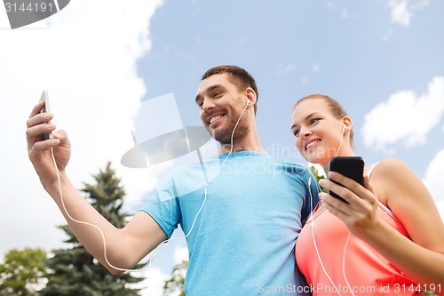 Image of two smiling people with smartphones outdoors