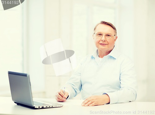 Image of old man in eyeglasses filling a form at home