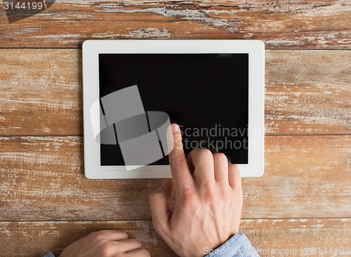 Image of close up of male hands with tablet pc on table
