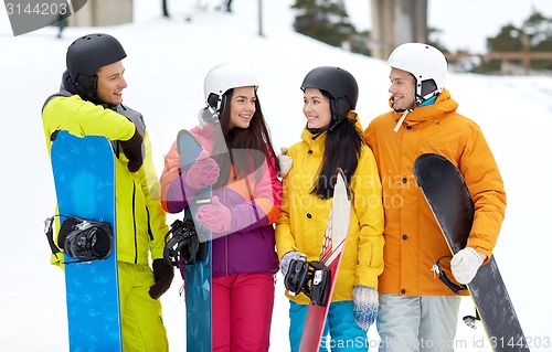 Image of happy friends in helmets with snowboards talking