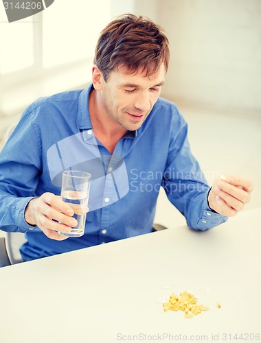 Image of ill man taking his pills at home