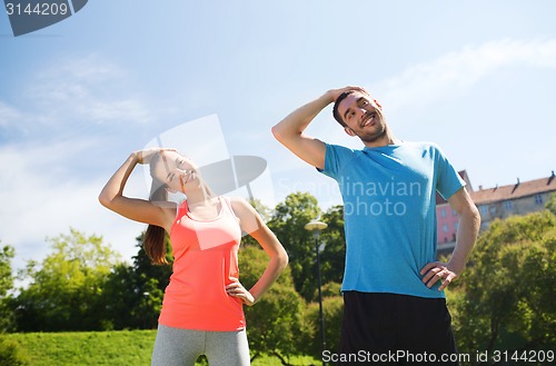 Image of smiling couple stretching outdoors