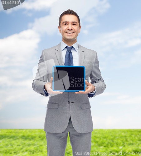 Image of happy businessman in suit showing tablet pc screen
