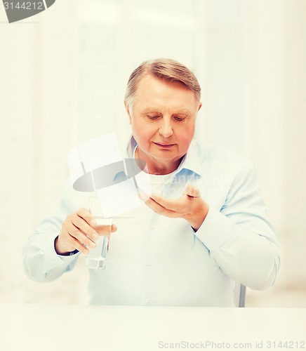 Image of old man with pills ang glass of water